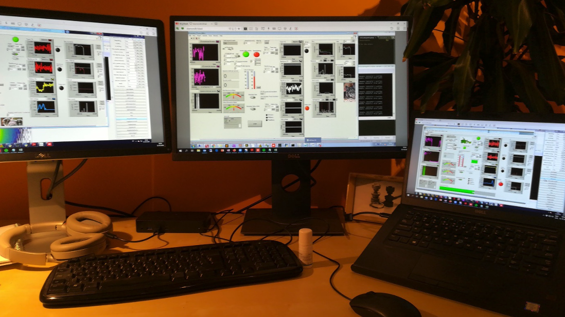 A photo of a desk with a laptop and external monitors, remotely connected to the computers in the laboratory.